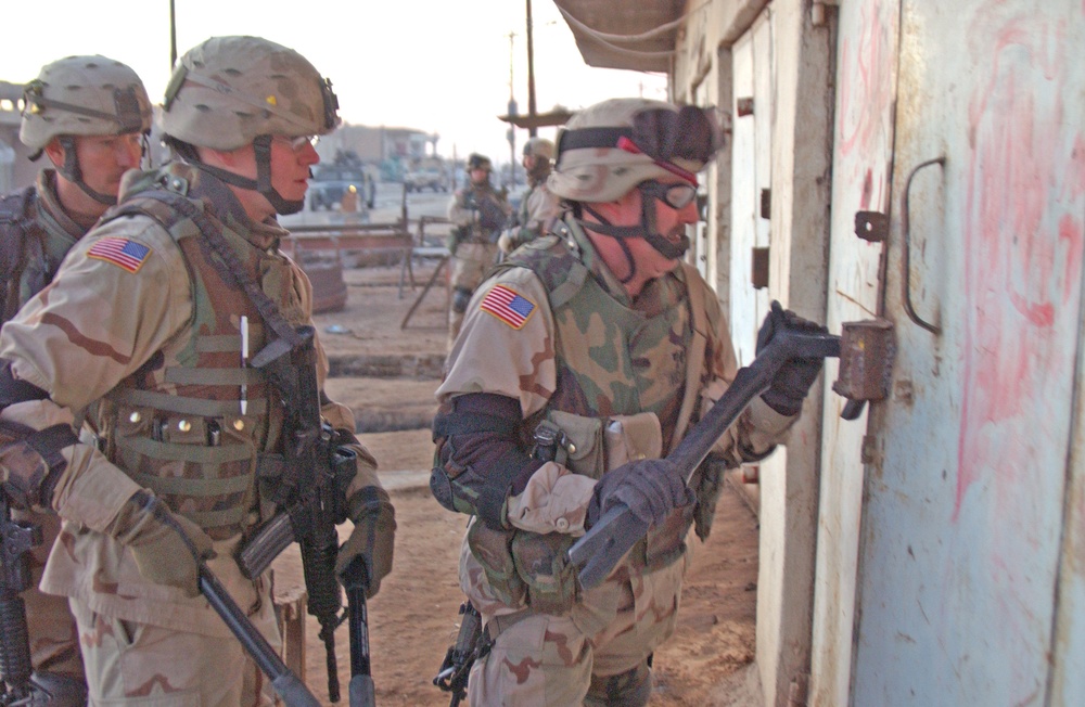 Spc. Kovach uses a hooligan bar to pry open the lock of a shed
