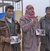 Three Iraqi men stand in front of a water pump