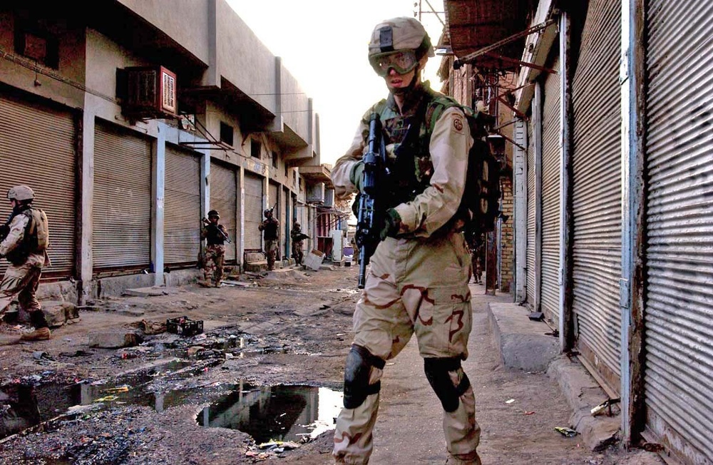 A paratrooper moves down a narrow alleyway