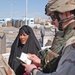 Spc. Viccari examines the paperwork of an Iraqi woman
