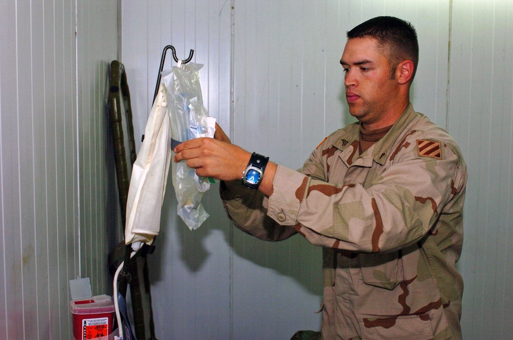 Sgt. Carver Adjusts the IV Bag at the Aid Station