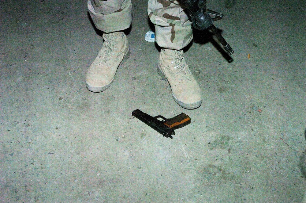 A Soldier Stands Guard Over a Pistol Found in a Vehicle