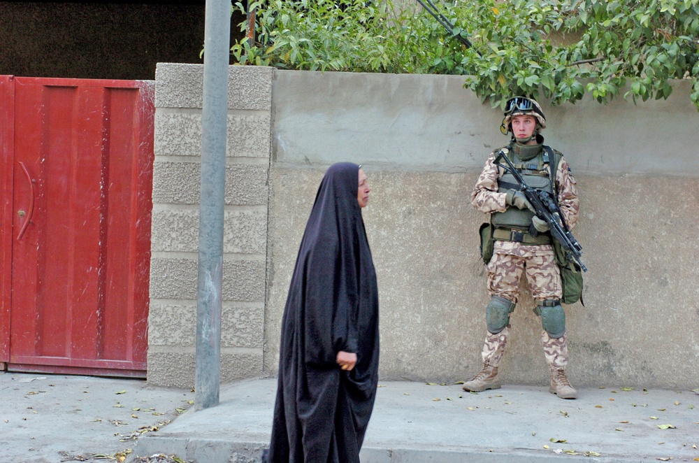 Cpl. Benno Ratmanov watches an Iraqi woman walk by