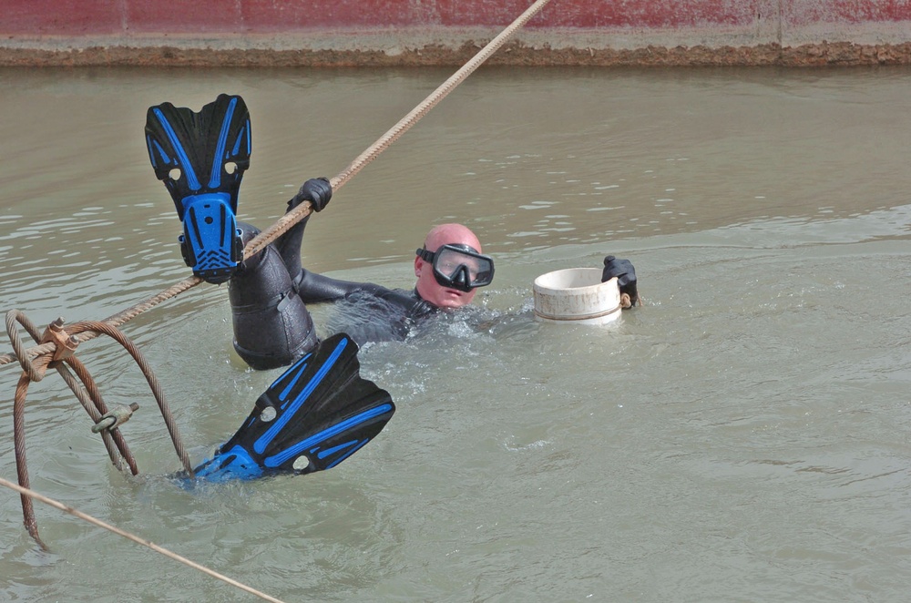 Sgt. Roberts holds the guide pipe while two divers secure it