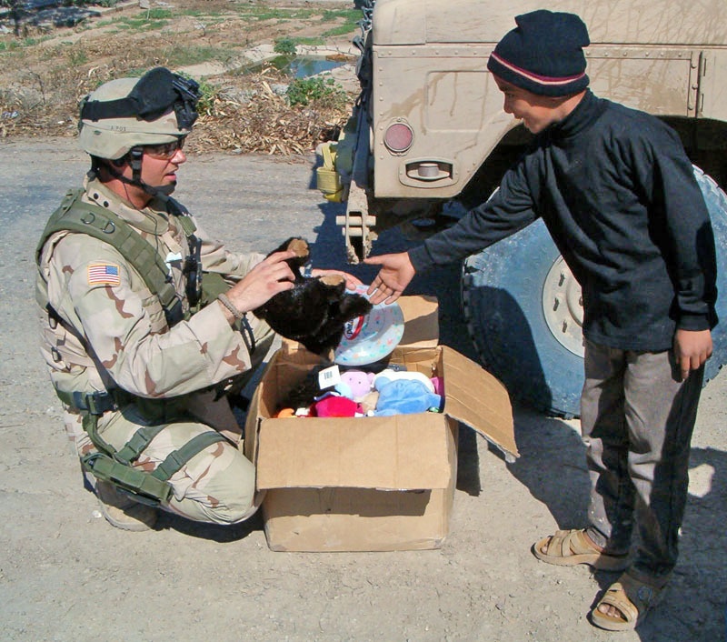 Spc. Jeff Sinclair Hands a Teddy Bear to an Iraqi Child
