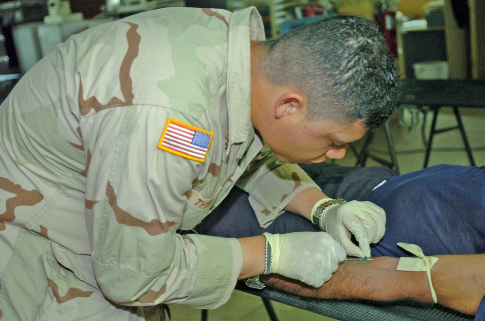 Pvt. Tyson rehydrates a Camp Bucca Internment Facility detainee