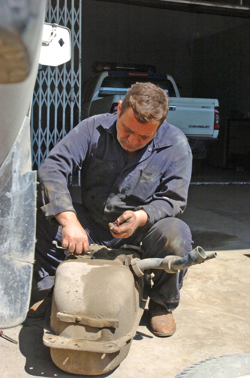 A Iraqi mechanic works on a gas tank