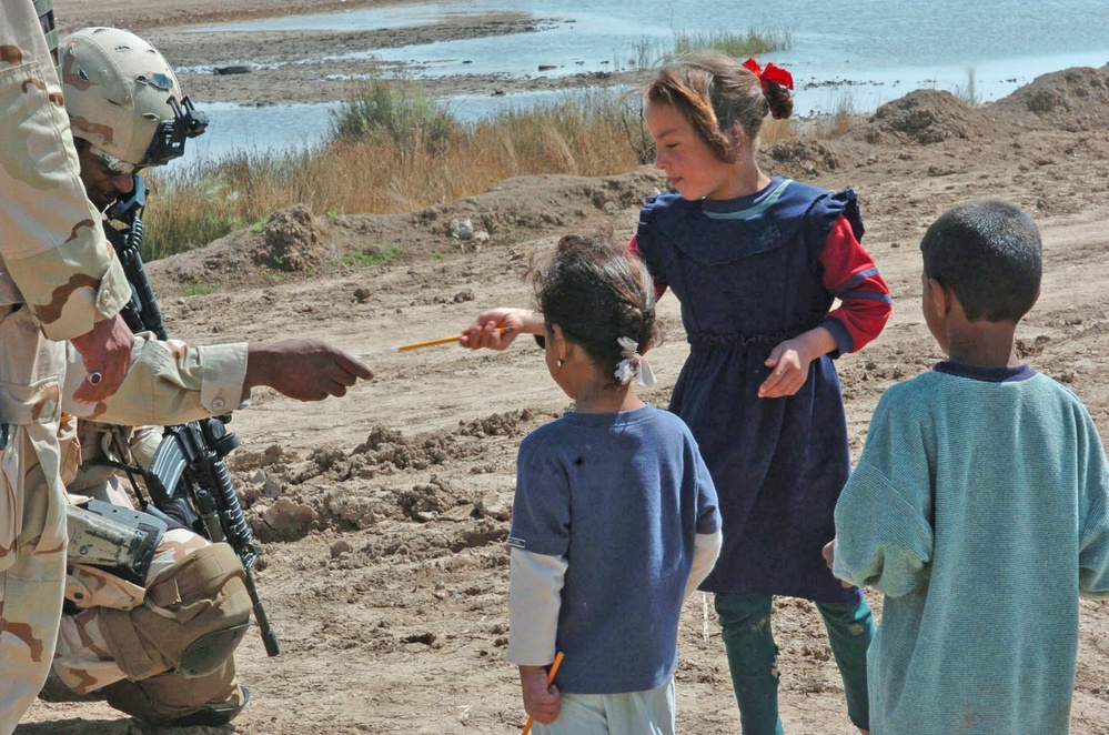 Staff Sgt. Stevie Knox hands out pencils to Iraqi children