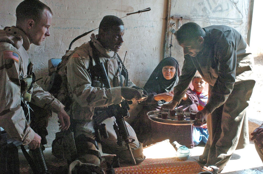 An Iraqi farmer, pours tea for Staff Sgt. Stevie Knox