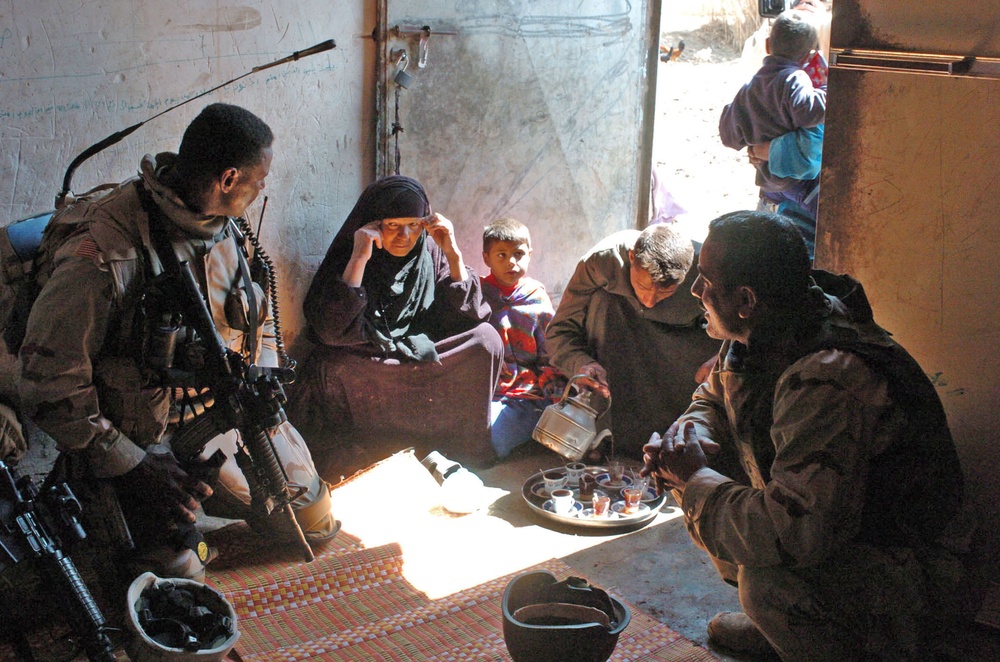 An Iraqi farmer, pours tea for Staff Sgt. Stevie Knox