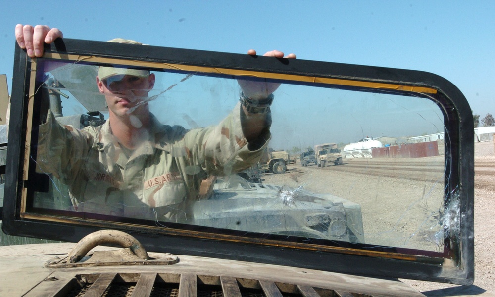 Sgt. Morris stands behind the winshield of the vehicle