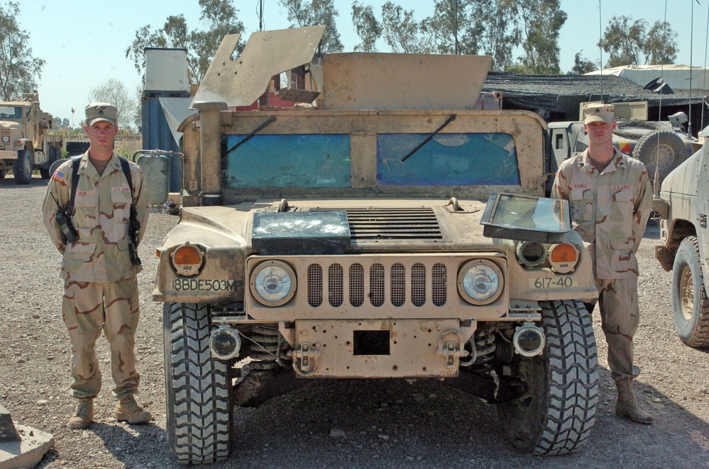 Two soldiers stand beside their recently repaired Humvee