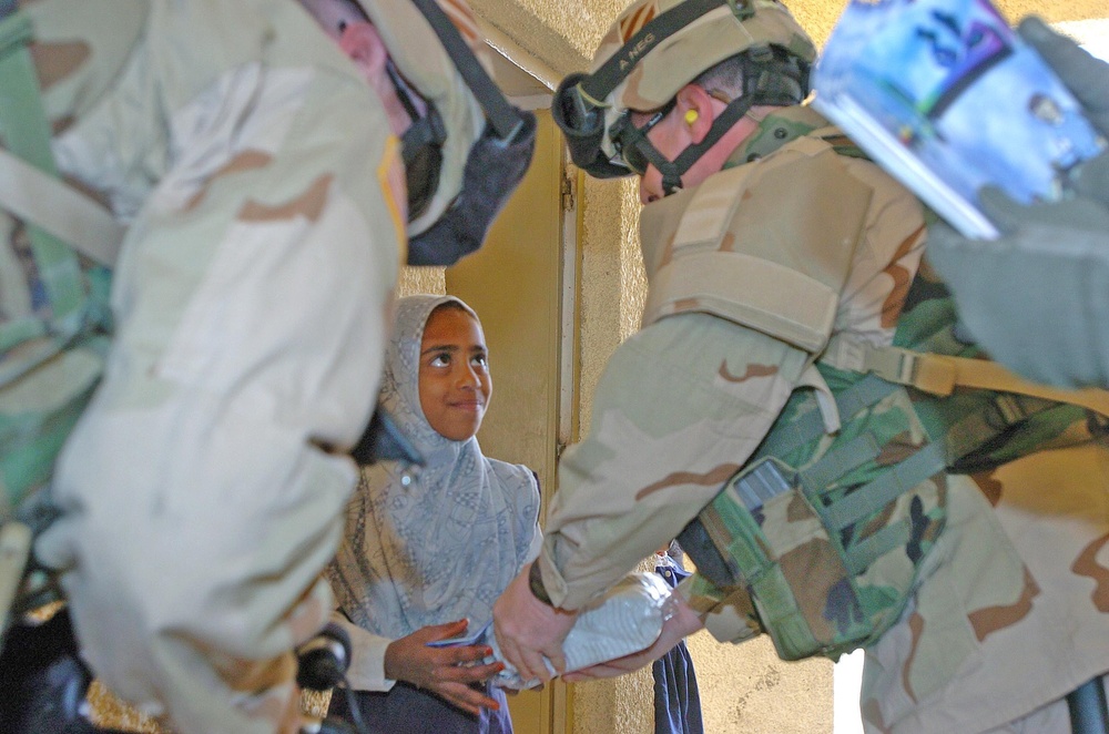 Chaplain hands a pair of sneakers and a coloring book to a stude