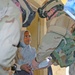 Chaplain hands a pair of sneakers and a coloring book to a stude