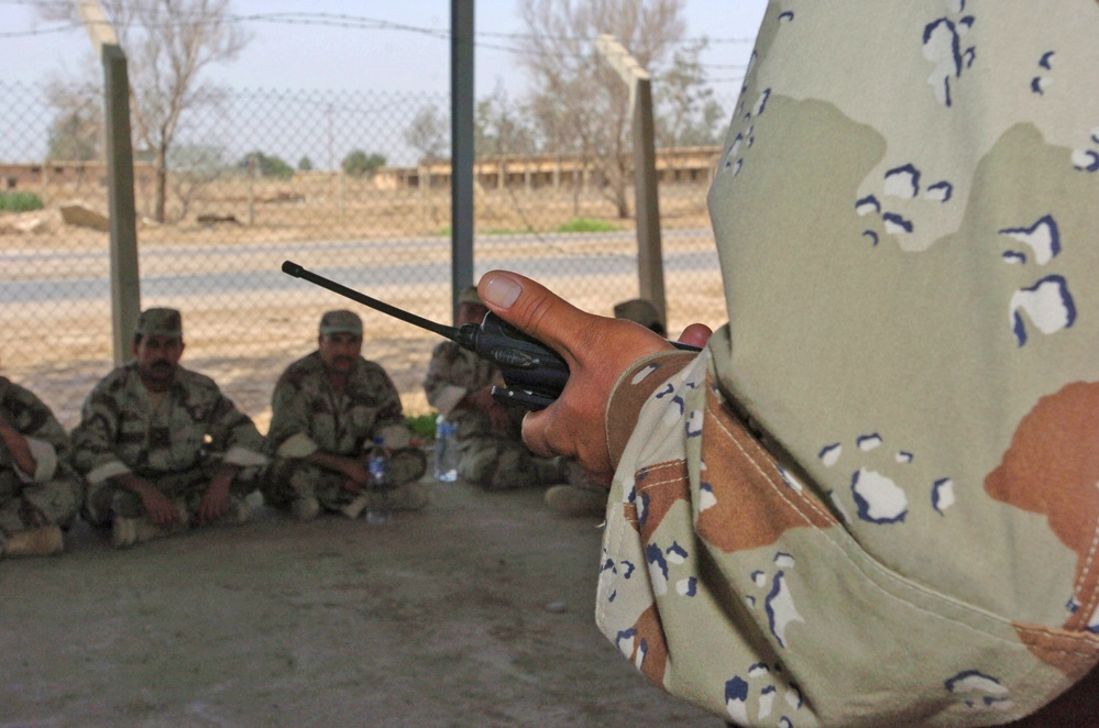 ING soldiers sit in the shade in a motor pool during a class