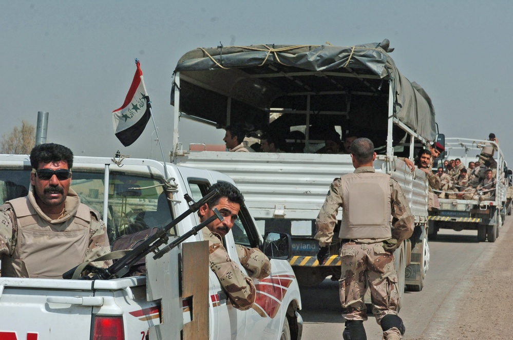 An Iraqi man pulls guard out of the back of a truck