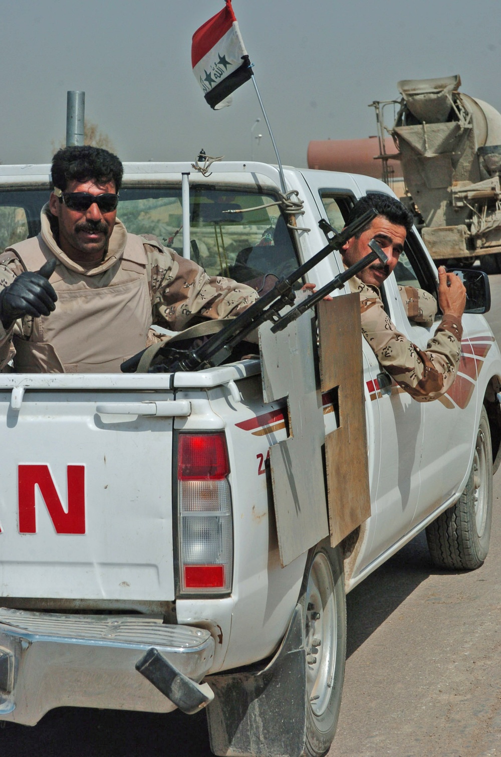 An Iraqi man pulls guard out of the back of a truck