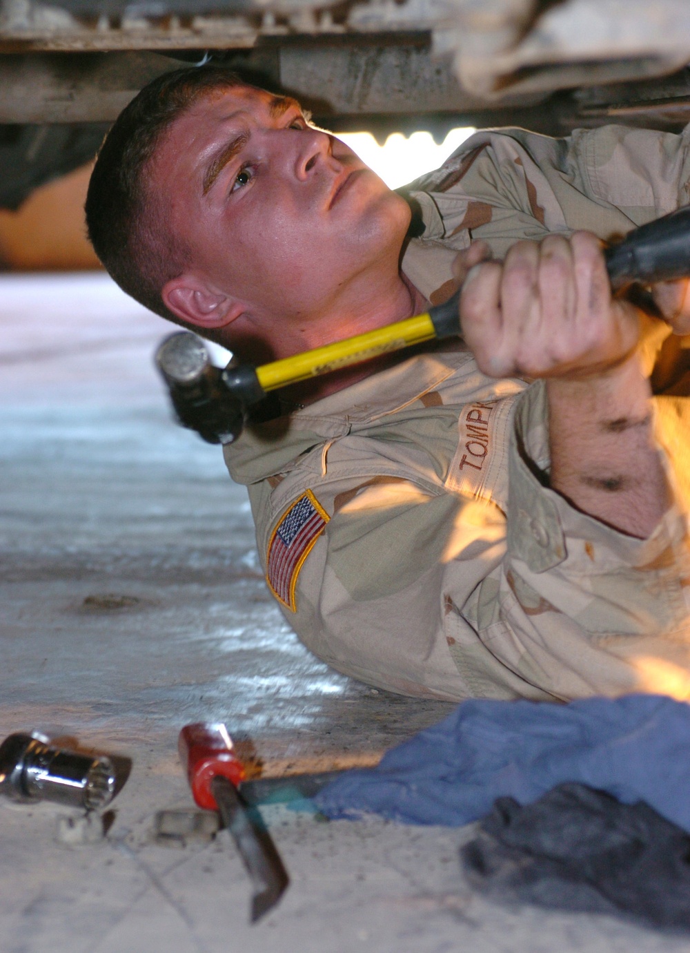 Spc. Tompkins hammers at a bolt on the gearbox