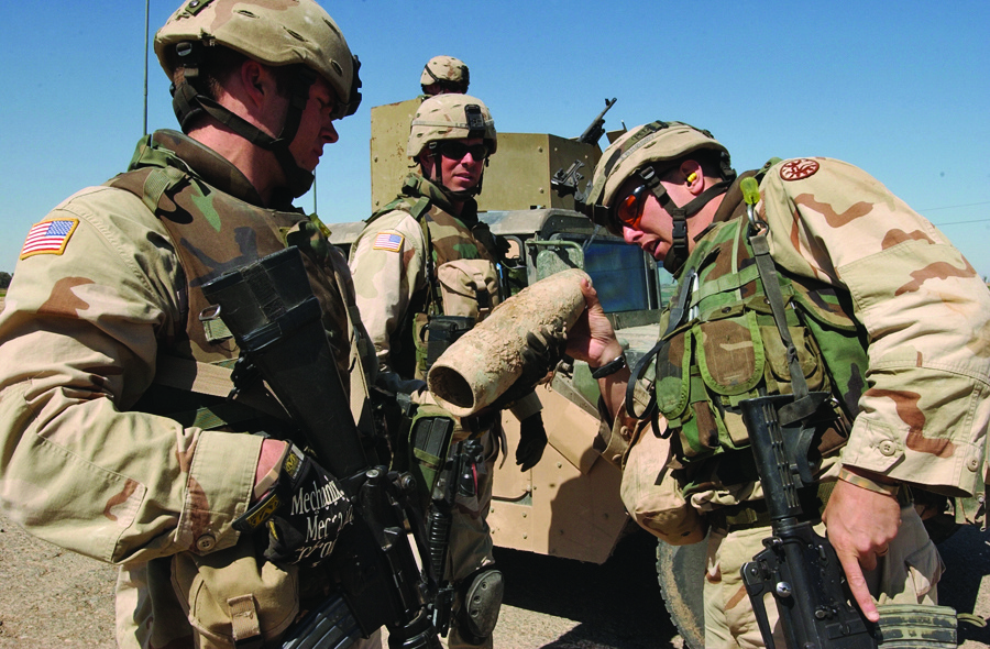 Two soldiers examine an artillery round founded