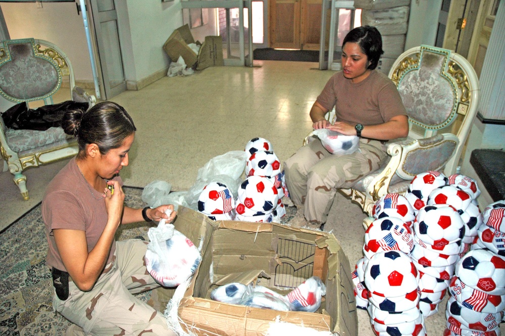 Two soldiers prep boxes full of soccer balls