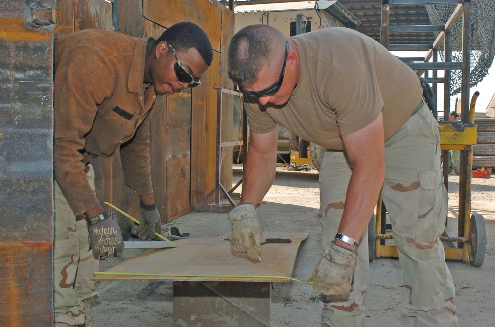Spc. Ross and Sgt. Steiner measures a piece of metal