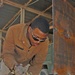 Spc. Michael D. Ross cuts out a piece of metal to use