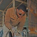 Spc. Michael D. Ross cuts out a piece of metal to use