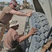 Two soldiers put a tire back on the 940th M1117