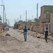 Iraqi Police officers secure an alley during a raid in Awhida