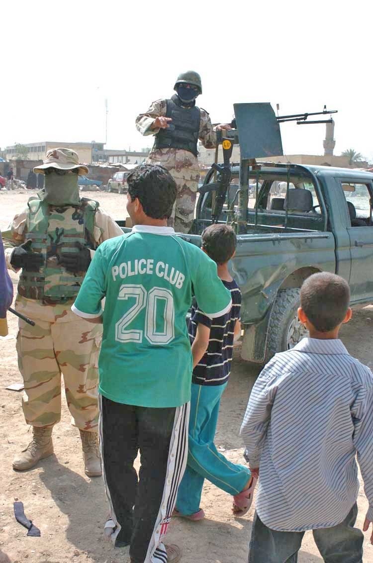 An Iraqi Army Soldier watches over residents of Sadr City