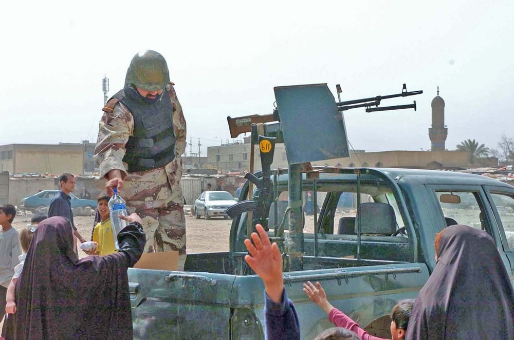 An Iraqi Army Soldier gives bottled water to residents