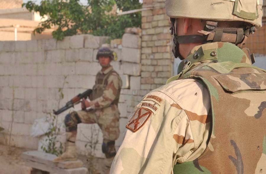 A Soldier observes a Iraqi Soldier pull security during a search