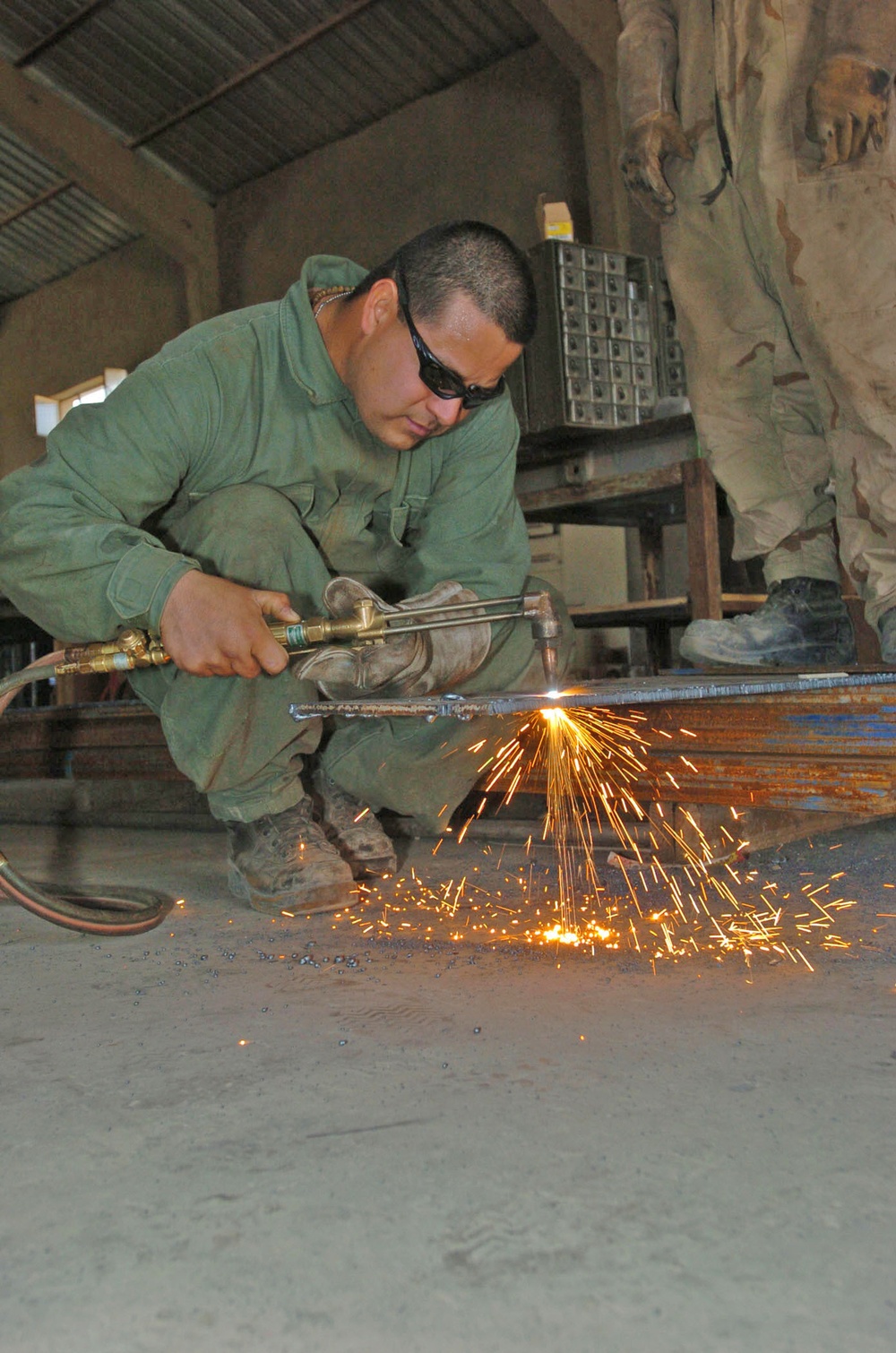 Spc. Alejandro Guevara cuts a piece of steel