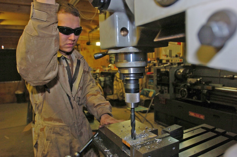 Spc. Paris uses a drill press while creating a bumper guard