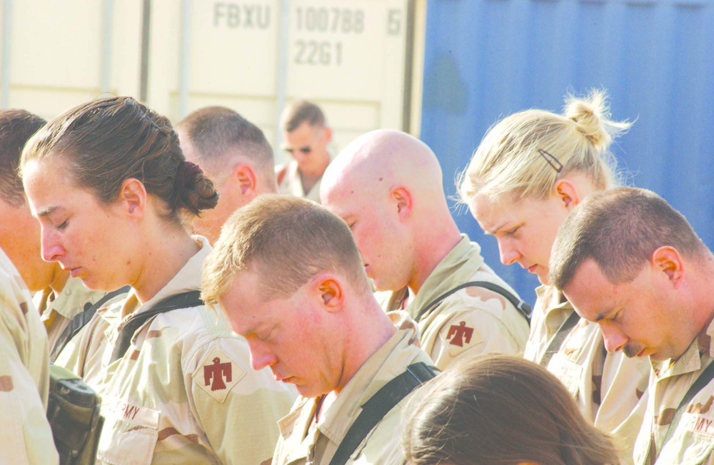 Soldiers bow thier heads during a memorial service