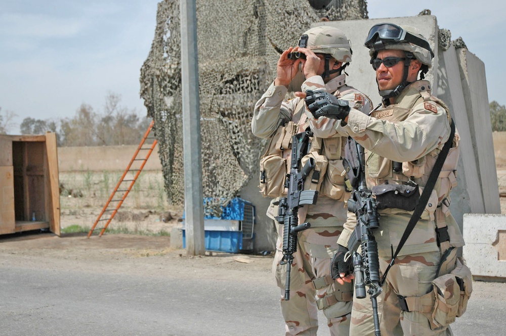 Sgt. Uesugi  points out Iraqi citizens on a rooftop