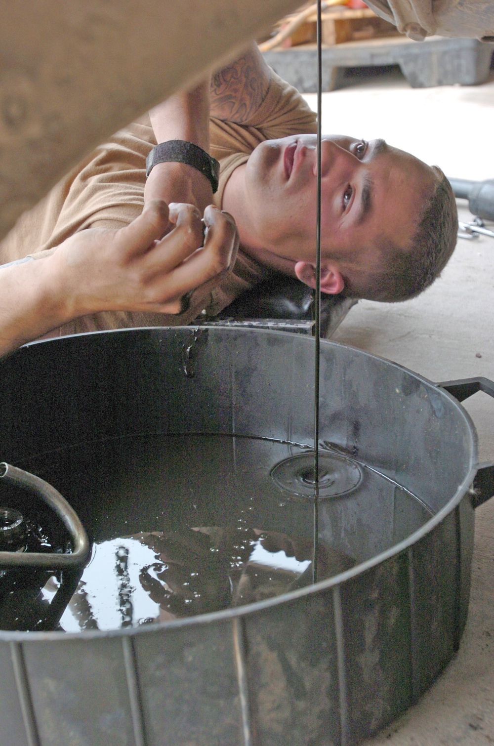 Spc. Greg Laperle watches the oil drain from his Humvee