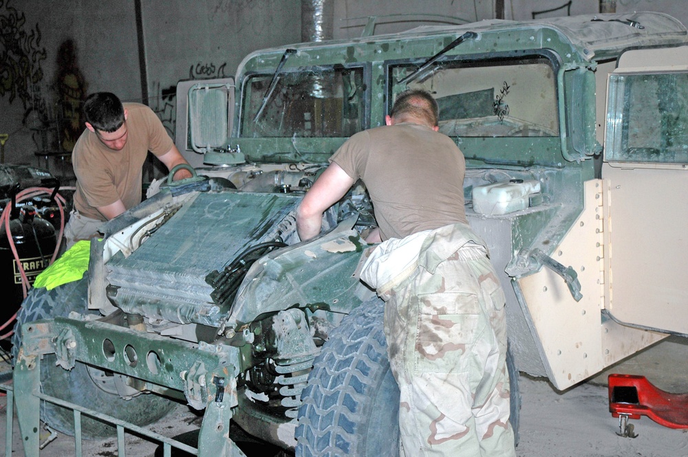 Two mechanics work on a M998 Humvee