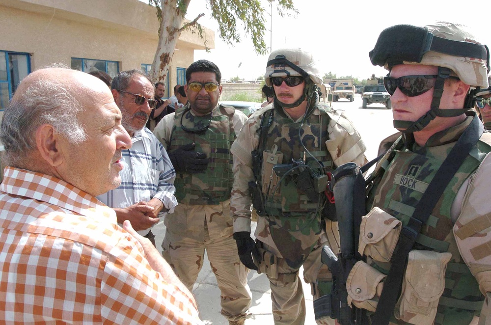 Soldiers speak with an operator of a water treatment facility