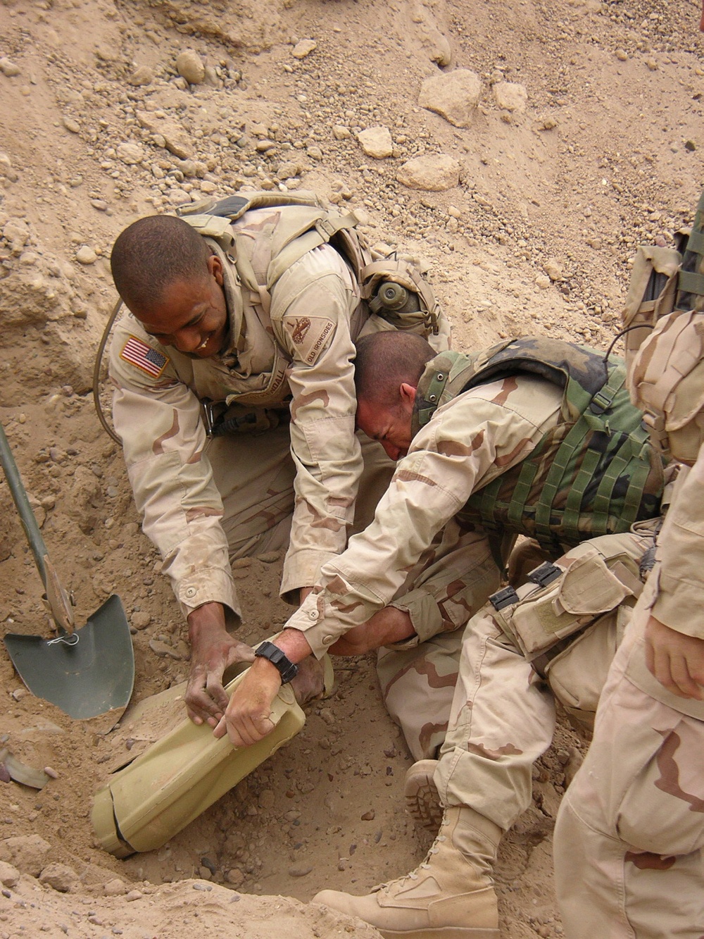 Soldiers work together to unearth a large weapons cache