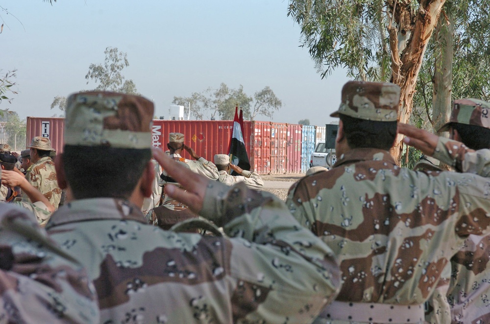 Soldiers salute the Iraqi flag during the playing of the Anthem