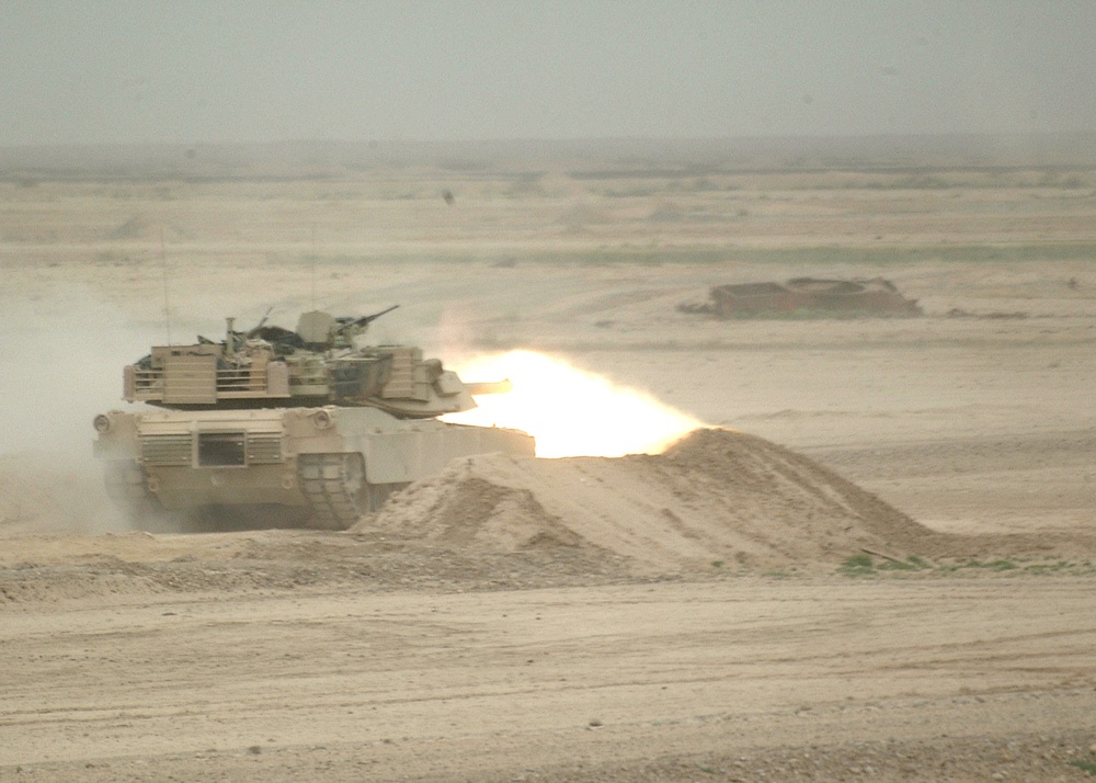 A tank crew engages a target with its 120 mm main gun