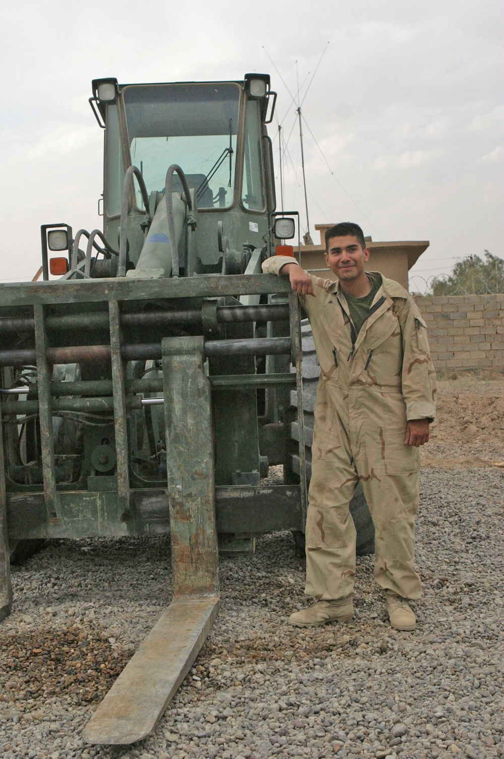 Lcpl. Simon Delgado stands next to a Tractor Rubber-Tired