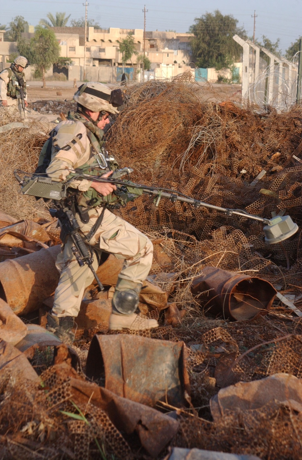 Spc. Robert Fairfax walks through a field of scrap metal