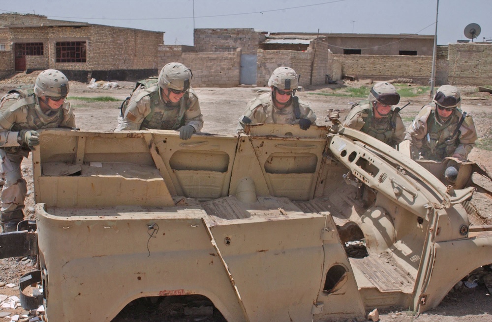 Soldiers turn what remains of a car over