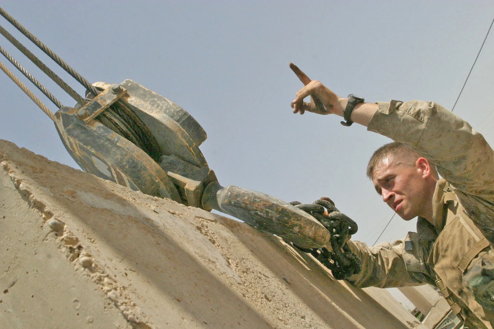 Lcpl. Bailey signals for the Marine operating an M88 tank