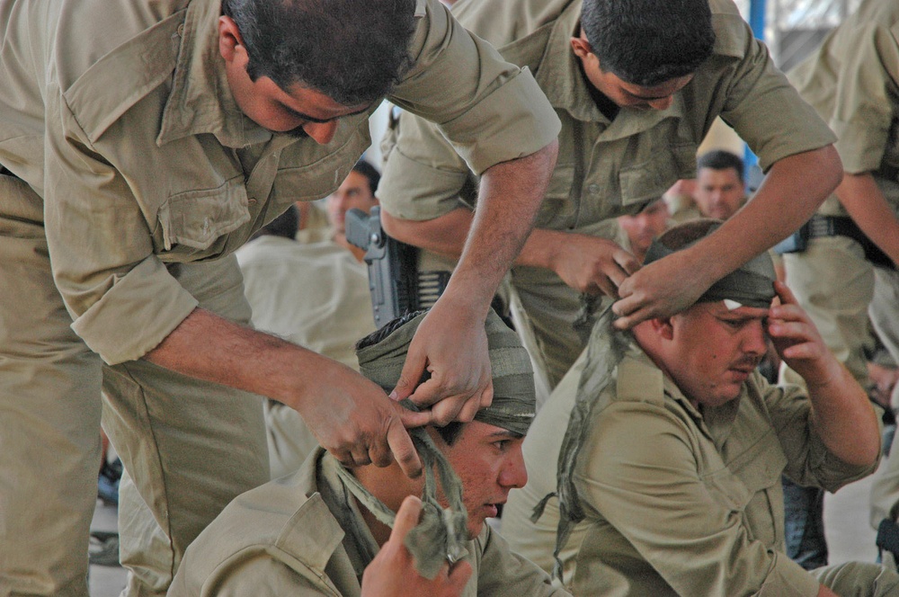 Iraqi police place bandages around each others heads