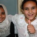 An Iraqi school girl gives the thumbs up alongside her friend