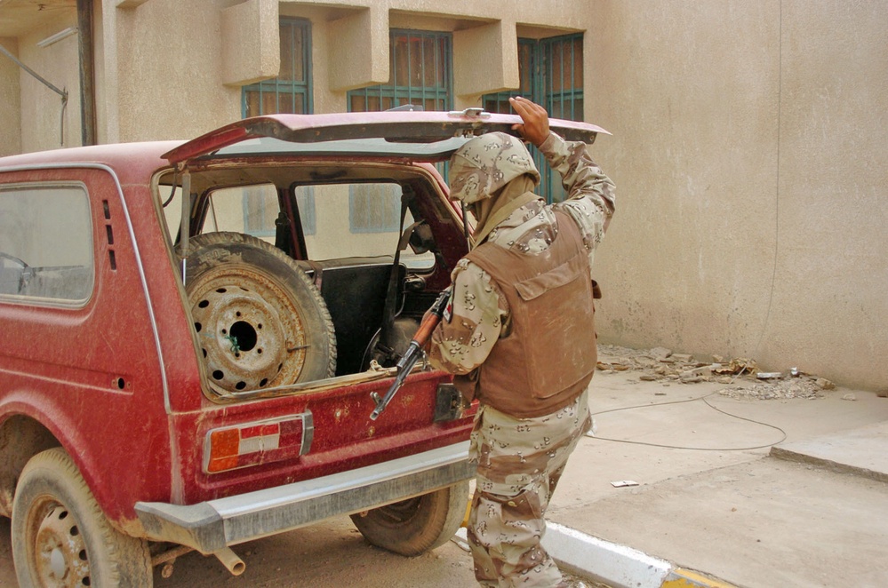 An Iraqi Soldier searches the back of vehicle