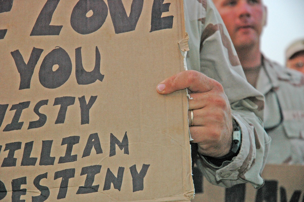 A Soldier holds a sign for his loved ones during the concert